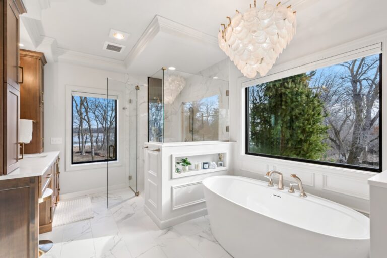 Luxurious bathroom with freestanding soaking tub, glass shower enclosure, marble flooring, and large windows overlooking