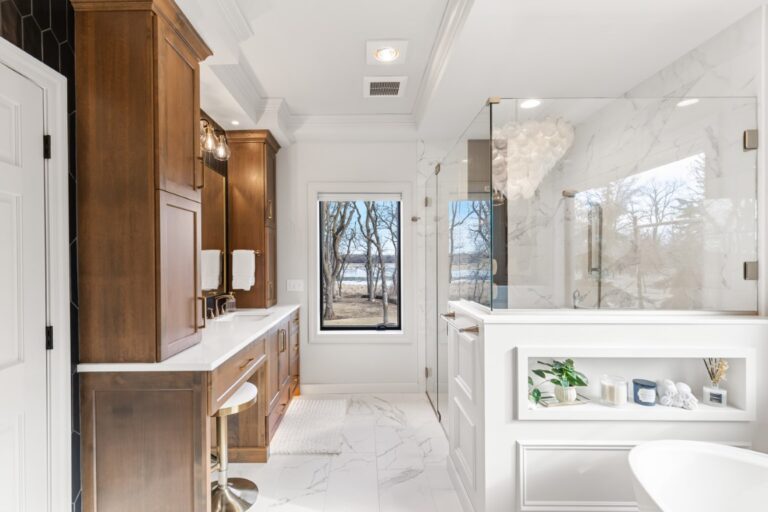 Modern luxury bathroom with dual vanities, walk-in shower, marble flooring, and wooden cabinetry