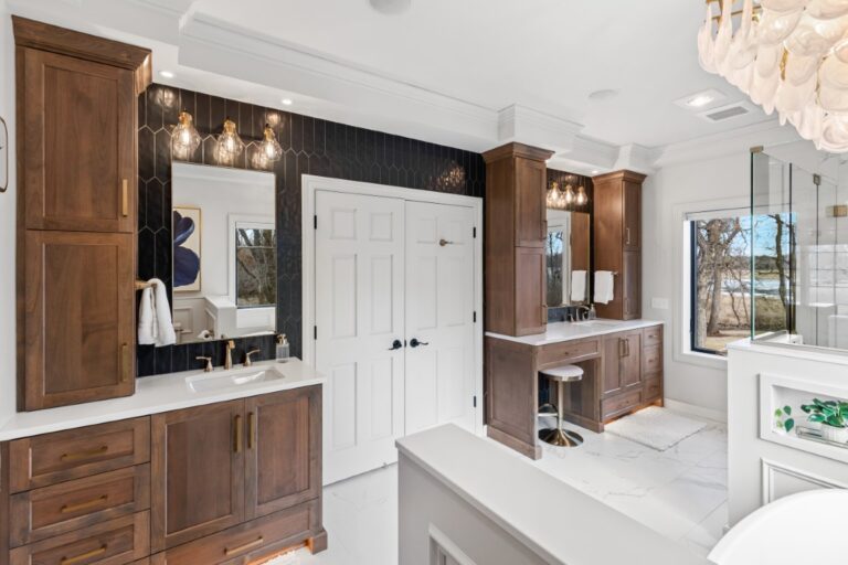 Modern bathroom with brown wood cabinetry, white subway tile walls, dual vanity sinks, and decorative shelving