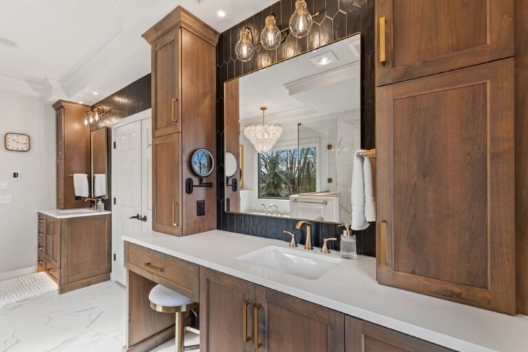 Modern bathroom with double vanity, wooden cabinets, marble countertop, large mirror, and pendant lighting