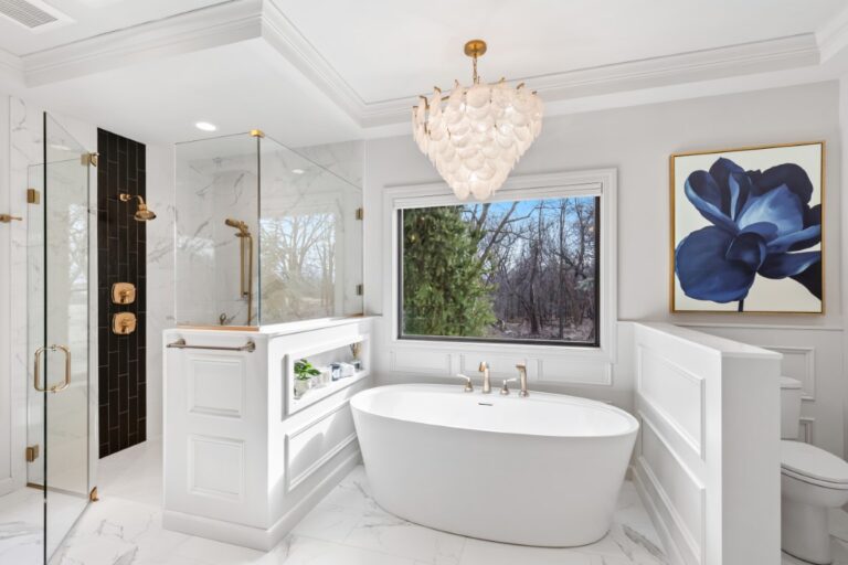 Luxurious modern bathroom with freestanding white tub, marble shower enclosure, crystal chandelier, and decorative wall art