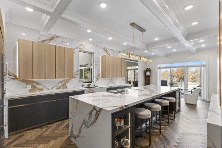 Modern kitchen with marble island, black lower cabinets, wood upper cabinets, stainless steel appliances, and coffered