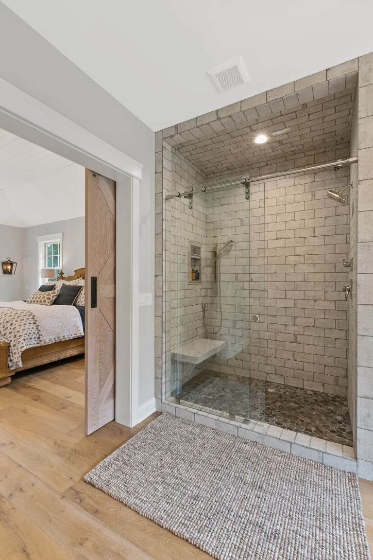 Modern bathroom with large walk-in shower, subway tile walls, and view to bedroom through doorway