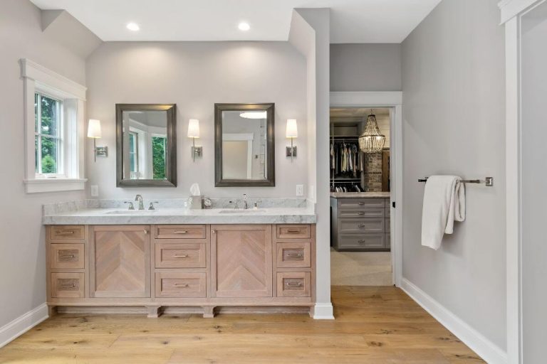 Modern bathroom with dual vanity, large mirror, wood cabinetry, and glass shower enclosure