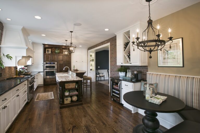 Modern kitchen with white cabinetry, dark wood flooring, island seating, stainless steel appliances, and pendant lighting