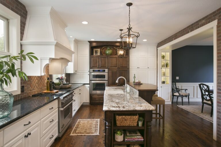 Modern kitchen with white cabinetry, marble island, stainless steel appliances, and open concept design