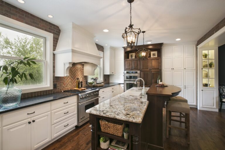 Modern kitchen with white cabinetry, dark island, granite countertops, and stainless steel appliances