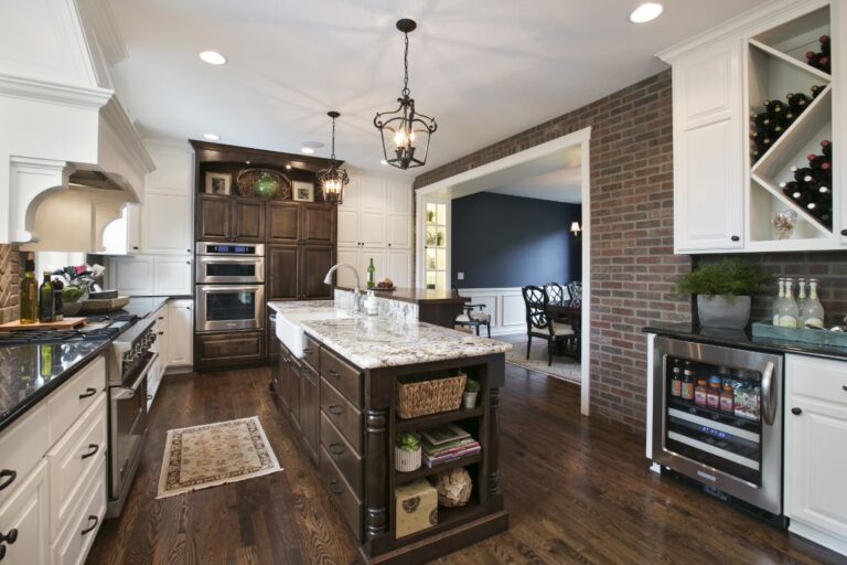 Modern kitchen with white cabinetry, dark wood island, brick fireplace, and stainless steel appliances