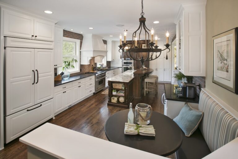 Modern kitchen and dining area with white cabinetry, wood flooring, island seating, and pendant lighting fixture