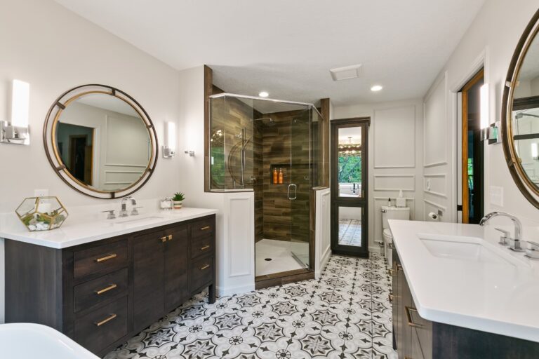 Modern bathroom with double vanity, walk-in shower, soaking tub, patterned tile flooring, and round mirrors