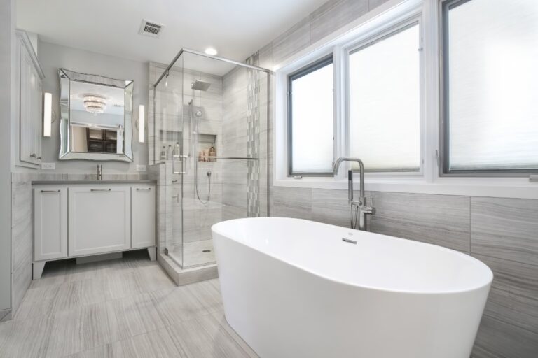 Modern bathroom with white freestanding tub, walk-in shower, and dual vanity with gray wood flooring