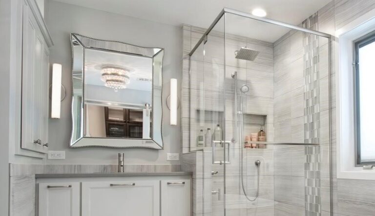 Modern bathroom with marble tile shower enclosure, white vanity, and framed mirror