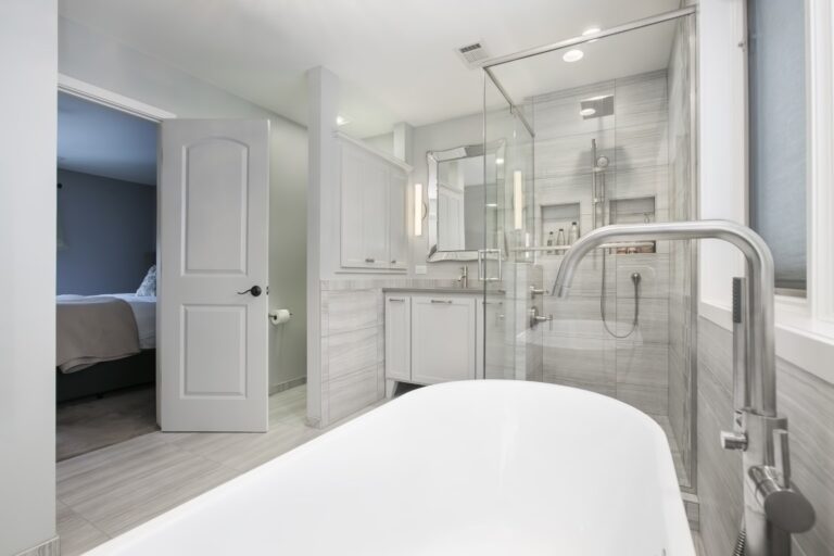 Modern bathroom with freestanding white tub, glass shower enclosure, and double vanity with mirror