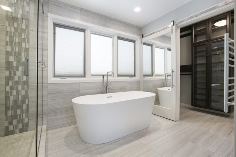 Modern master bathroom with freestanding white bathtub, walk-in shower, and mosaic tile accents
