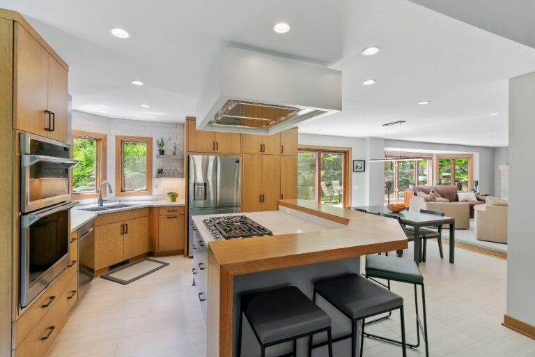 Modern kitchen with wood cabinetry, island seating, stainless steel appliances and bright natural lighting