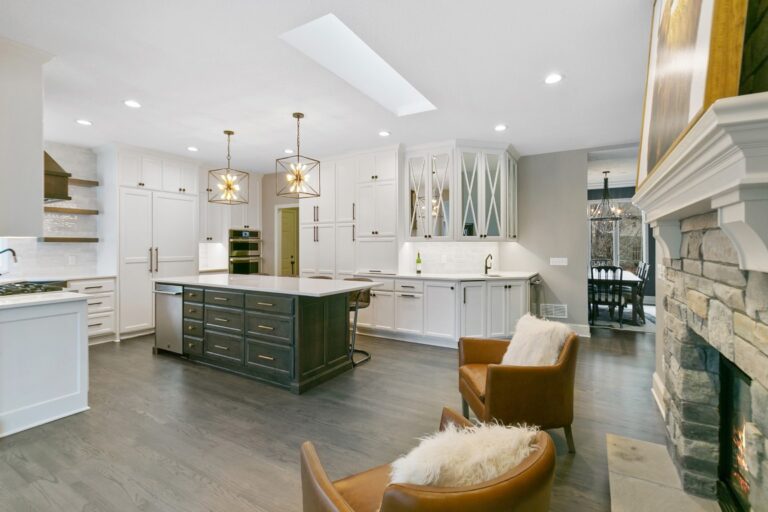 Modern kitchen with white cabinetry, green island, stainless steel appliances, and pendant lighting