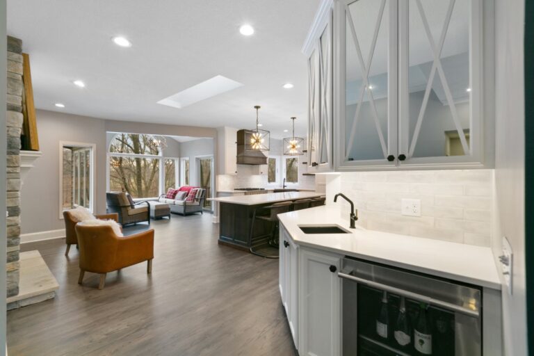 Modern open-concept kitchen and living room with white cabinetry, stainless steel appliances, and hardwood flooring