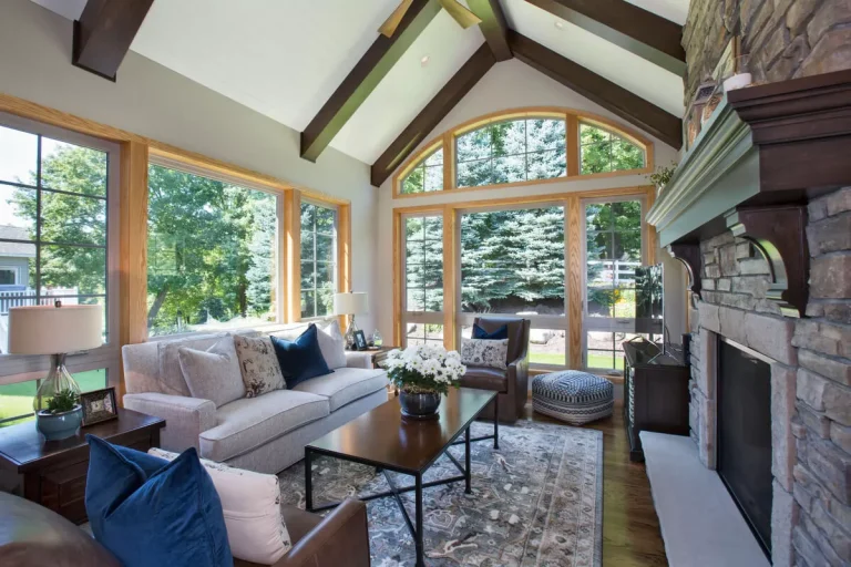 Modern living room with vaulted ceilings, large windows, fireplace, and contemporary furnishings overlooking a garden
