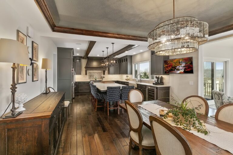 Modern open-concept kitchen and dining area with wood flooring, stainless steel appliances, and contemporary pendant lighting