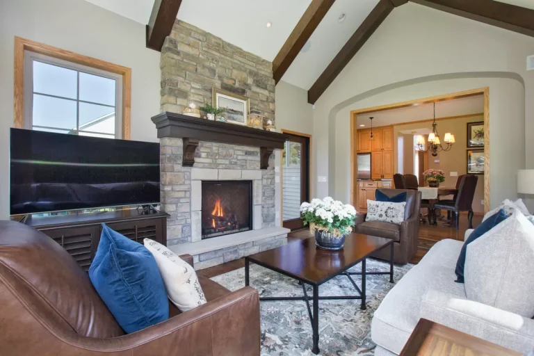 Modern living room with fireplace, leather sofa, blue pillows, wooden beams, and arched doorway
