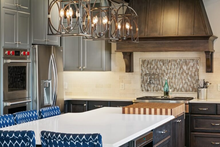 Modern kitchen with blue and white cabinetry, marble countertops, stainless steel appliances, and pendant lighting