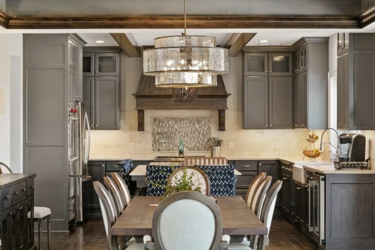Modern kitchen and dining area with gray cabinetry, marble countertops, pendant lighting, and wood dining table with