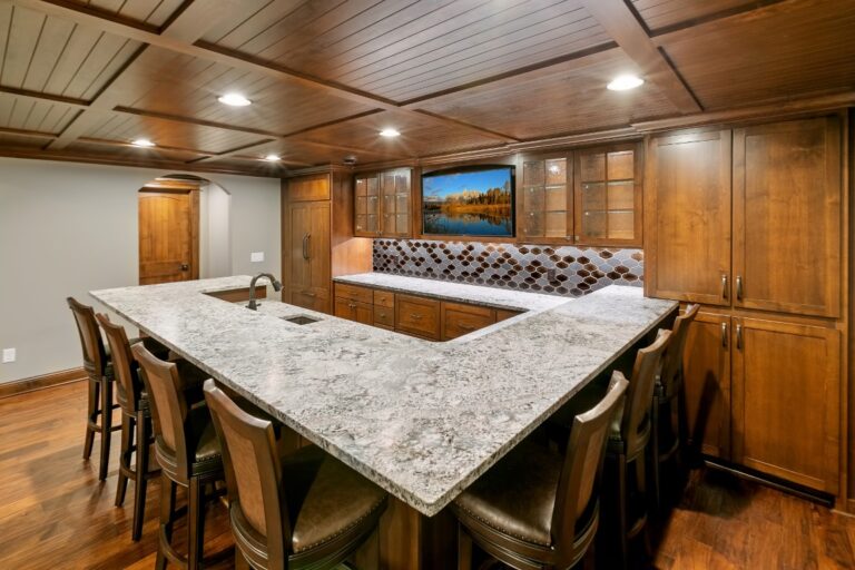 Luxury yacht galley featuring marble countertop, wooden cabinetry, dining area, and berth with patterned bedding