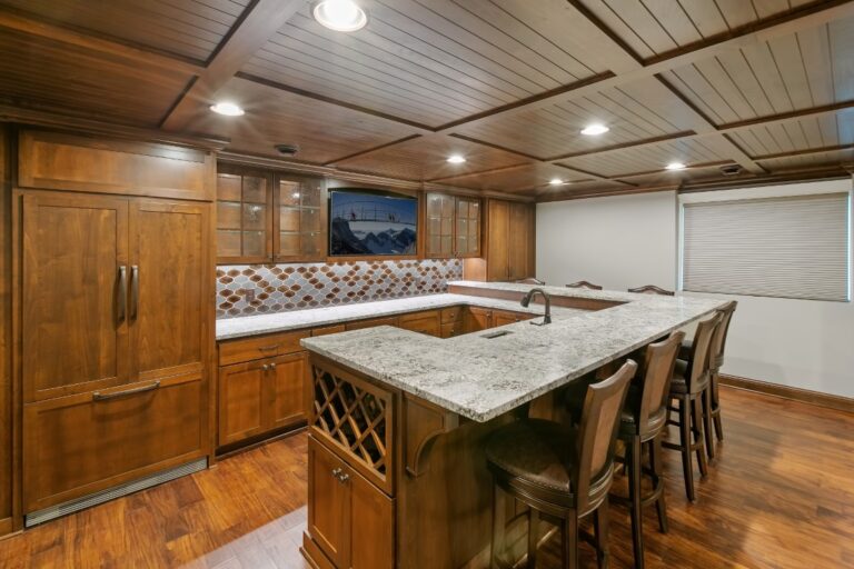 Spacious wooden kitchen with island, dining table, stainless steel appliances, and recessed ceiling lights
