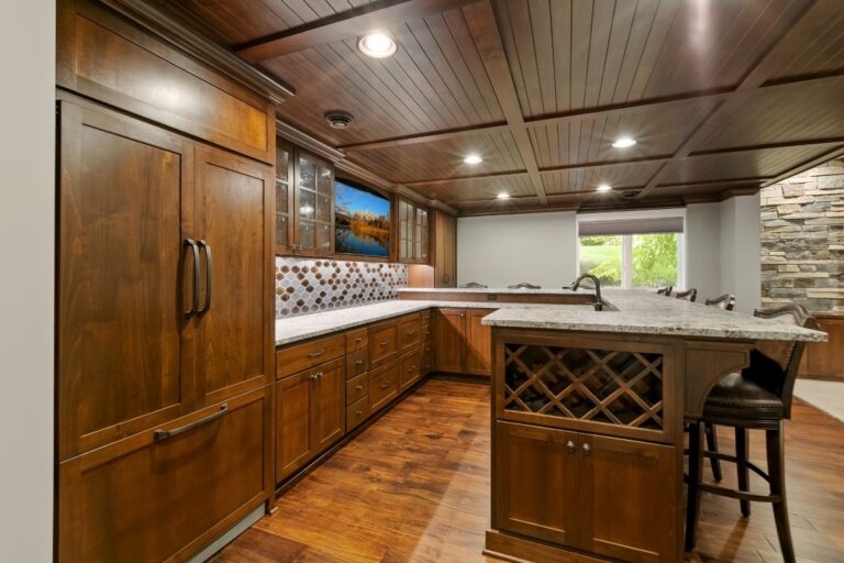 Modern kitchen with wood cabinetry, granite countertops, stainless steel appliances, and bar seating area