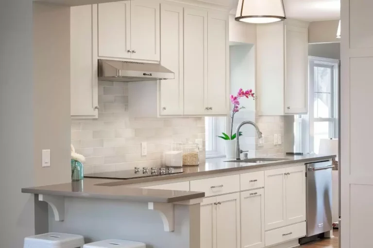 Modern kitchen with white cabinetry, stainless steel appliances, gray countertop, and pendant lighting above the sink