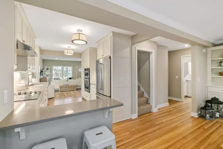 Modern kitchen with open floor plan, white cabinetry, island with sink, and hardwood floors