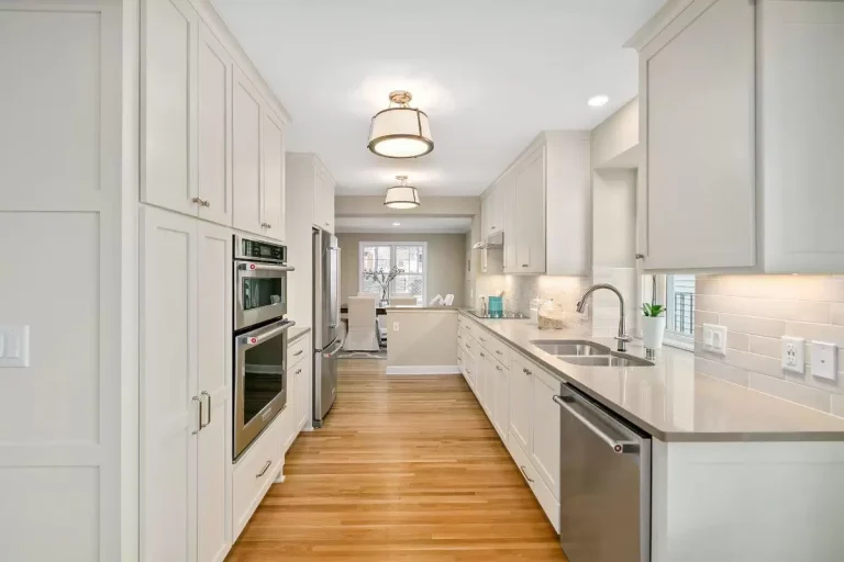 Modern kitchen with white cabinetry, stainless steel appliances, white countertops, and hardwood flooring