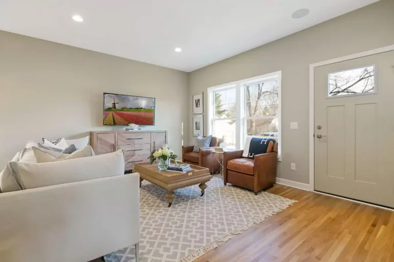 Bright living room with hardwood floors, beige walls, contemporary furniture, and large windows overlooking a snowy outdoor
