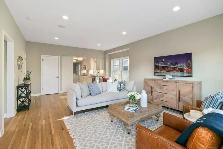 Modern living room with light blue sofa, wooden furniture, hardwood floors, and recessed ceiling lights
