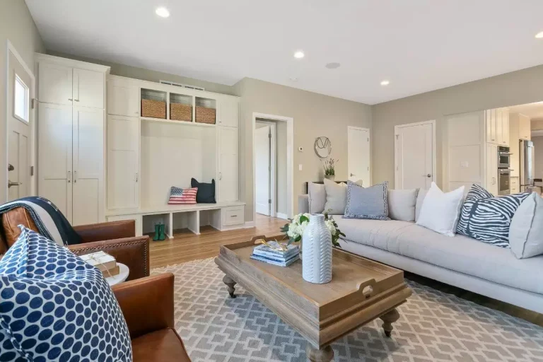 Modern living room with light blue sofa, wooden coffee table, built-in storage shelving, and blue patterned area rug