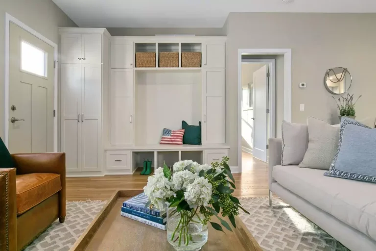 Bright, modern living room with gray sofa, wooden furniture, white built-in shelving, and fresh white flowers on a coffee