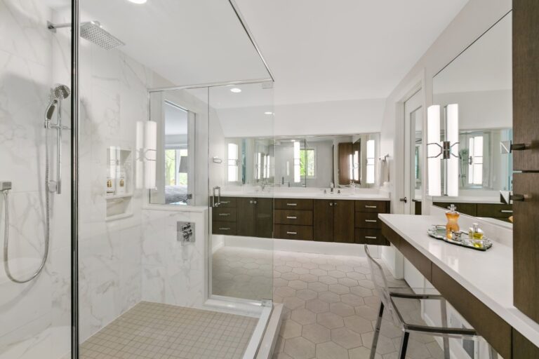 Modern luxury bathroom with dual vanities, glass shower enclosure, and marble countertops