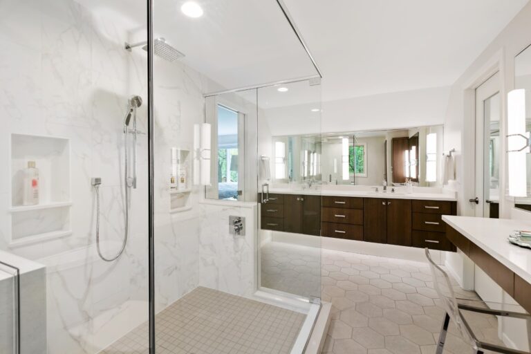 Modern luxury bathroom with marble shower, dual vanity, wooden cabinetry and white subway tile flooring