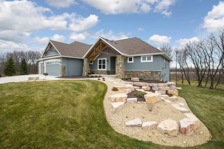 Large two-story residential home with brick and siding exterior, three-car garage, landscaped front yard with stone pathway