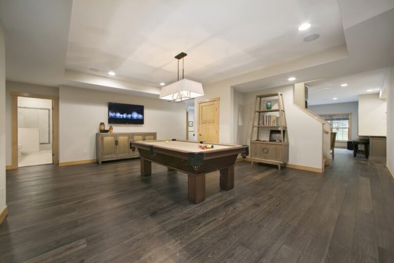 Modern showroom with pool table, pendant lighting, and dark wood flooring in an open floor plan