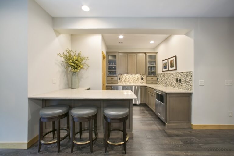 Modern kitchen with island, bar seating, stainless steel appliances, and granite countertops under pendant lighting