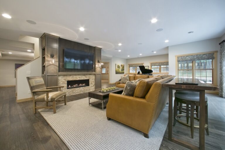 Modern living room with fireplace, mounted TV, gold sectional sofa, recessed lighting, and hardwood flooring