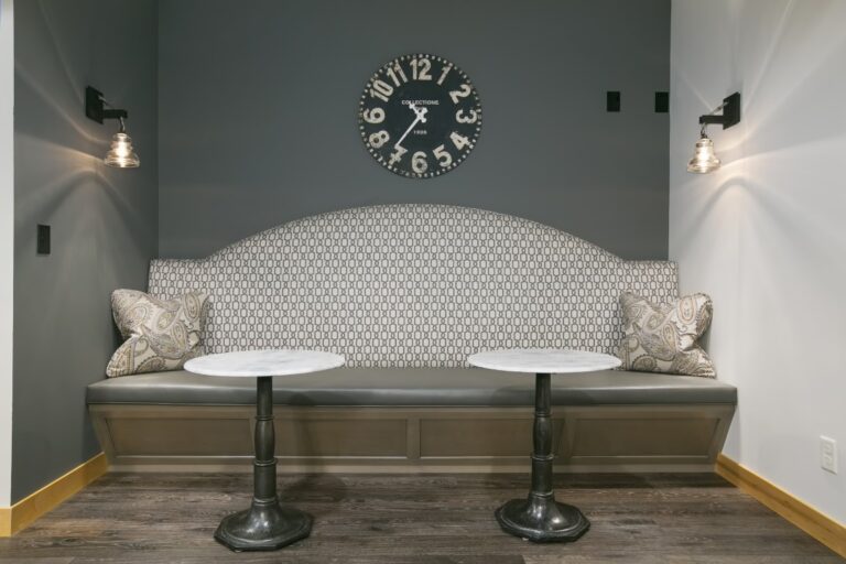 Modern bedroom alcove with built-in bench seating, patterned headboard, and decorative wall sconces