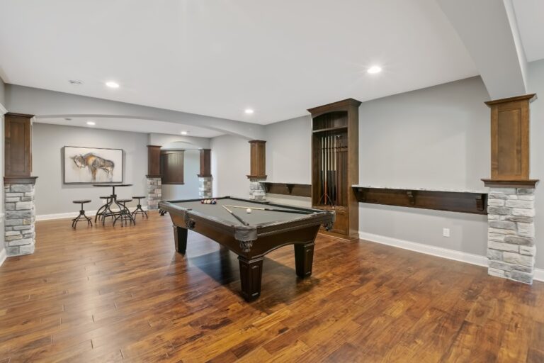 Spacious basement recreation room with pool table, recessed lighting, wood flooring, and stone accent walls