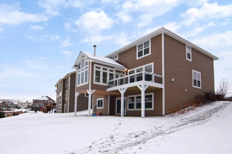 Two-story brick house with white trim and attached garage in winter snow setting