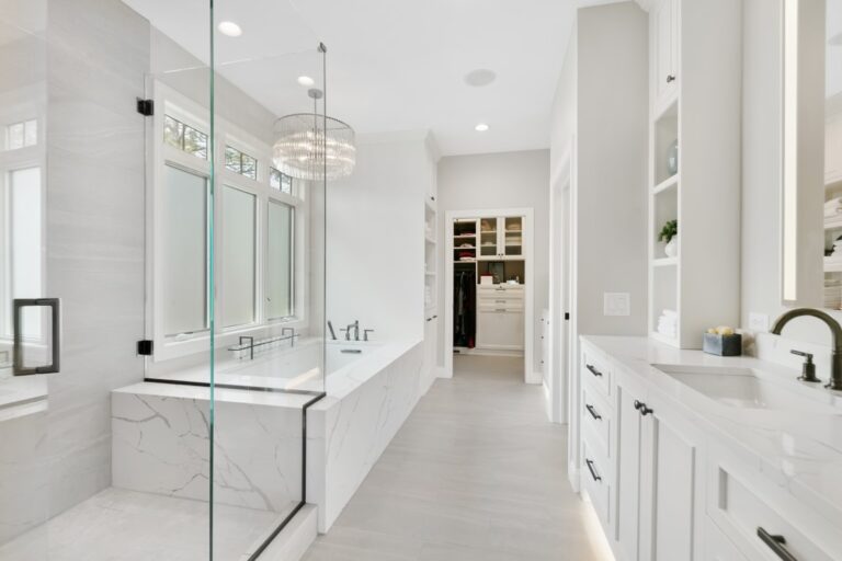 Modern luxury bathroom with white subway tile walls, freestanding bathtub, glass shower enclosure, and dual vanity sink