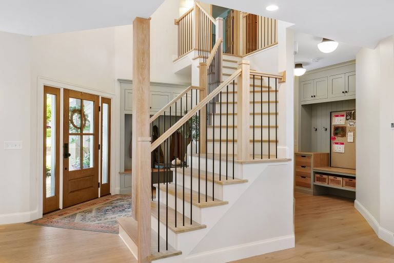 Modern home entryway with wooden staircase, glass door, hardwood floors, and contemporary interior design