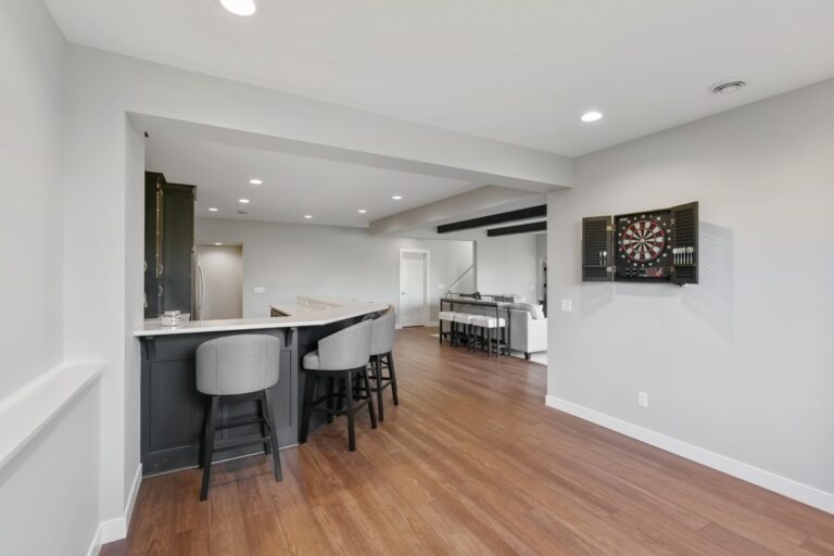 Modern kitchen and dining area with dark bar stools, wooden flooring, and stainless steel appliances