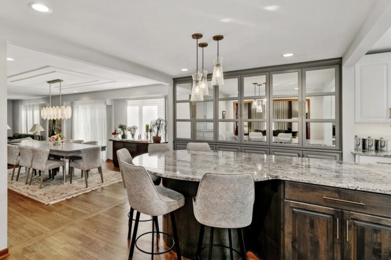 Modern kitchen with marble island, stainless steel appliances, white cabinetry, and open dining area