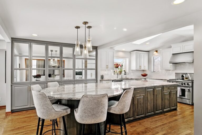 Modern kitchen with white cabinetry, dark wood island, pendant lighting, and dining seating for four